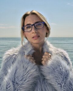 Mujer con gafas de lectura por presbicia a los 40 frente al mar
